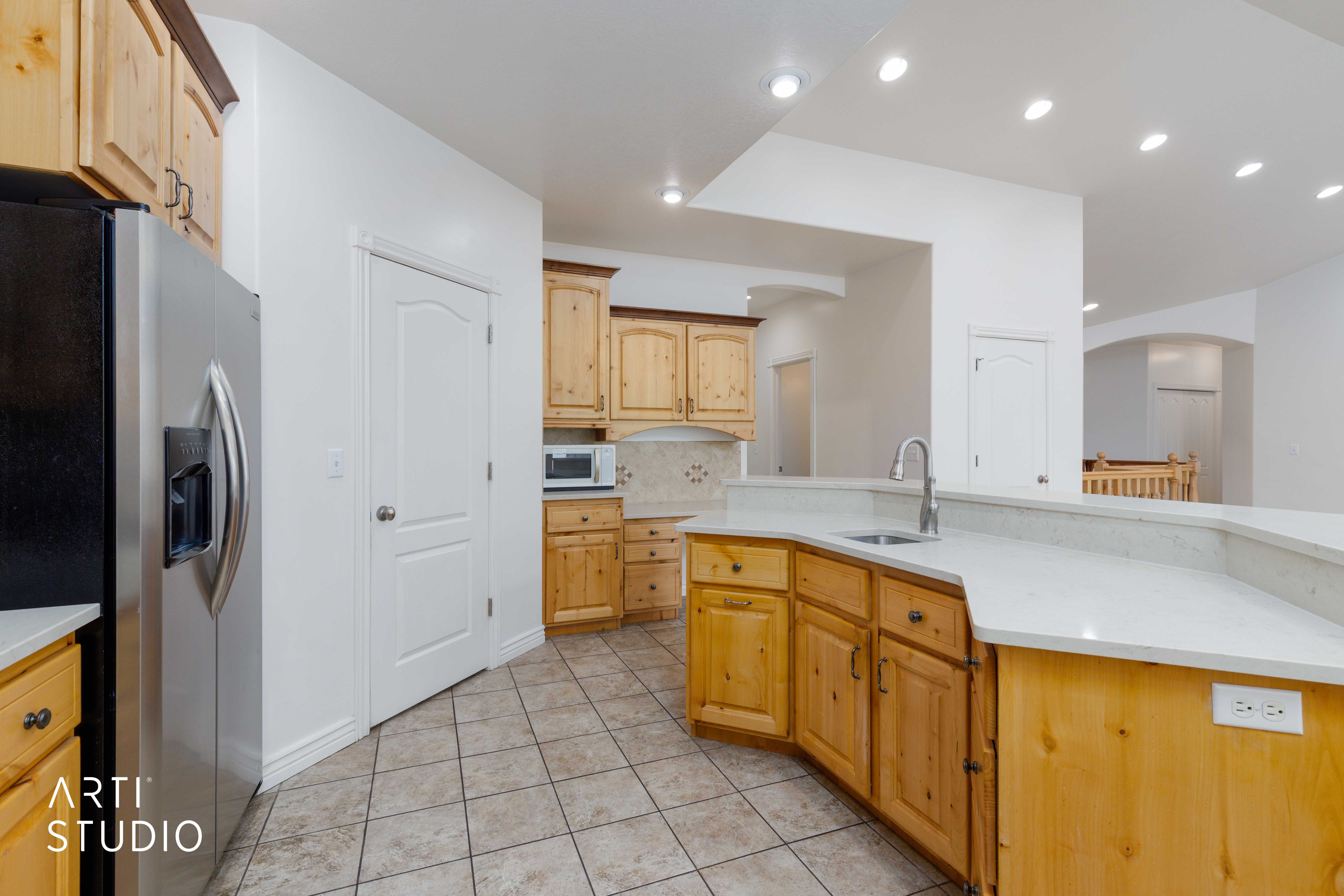 Kitchen featuring wood cabinetry, light-toned countertops, a stainless steel sink with a gooseneck faucet, recessed lighting, and tiled flooring