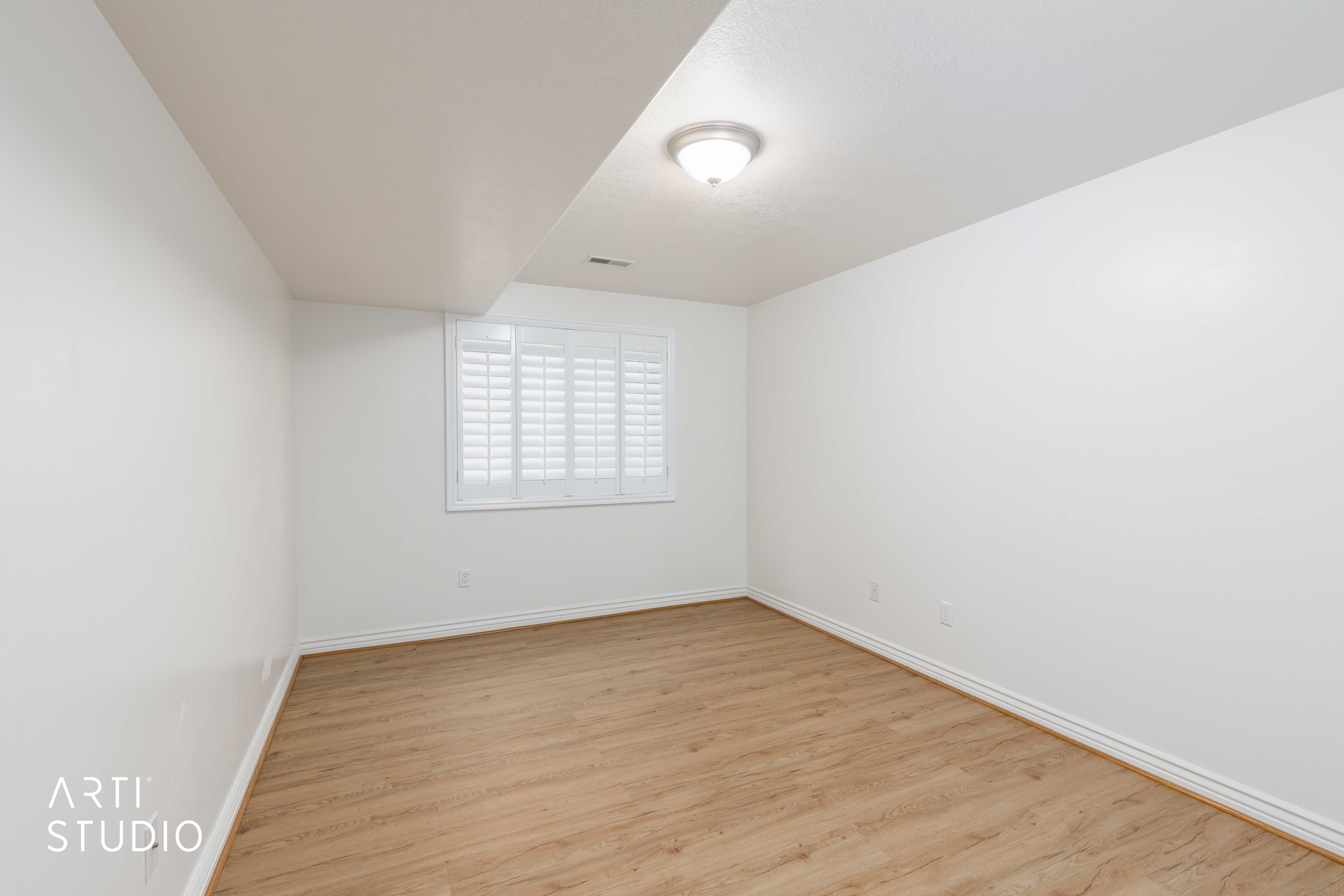 Spacious room featuring wood-finish flooring and white walls