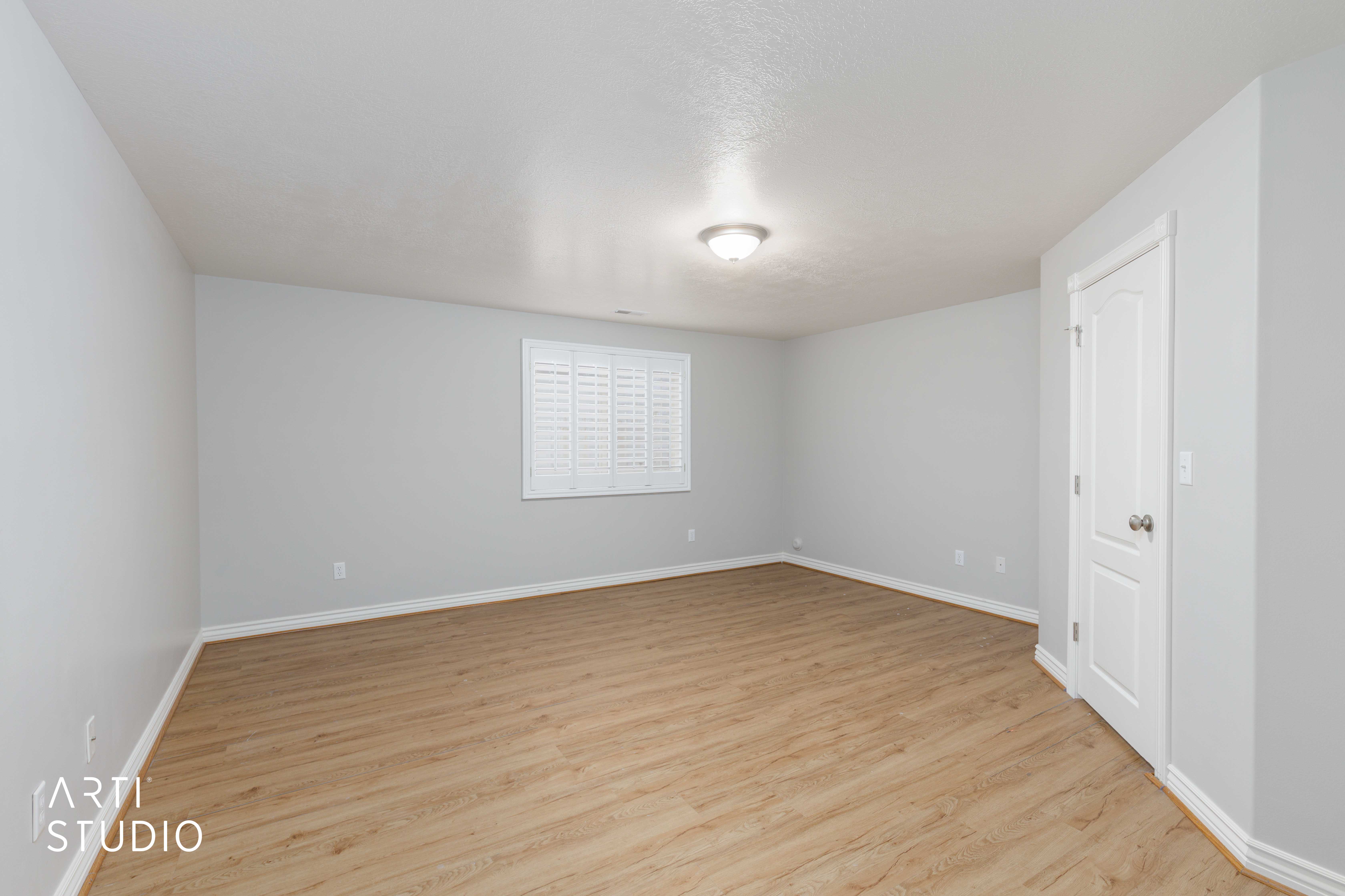 Spacious room featuring wood-finish flooring, light grey walls, and white baseboards