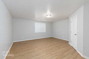 Spacious room featuring wood-finish flooring, light grey walls, and white baseboards