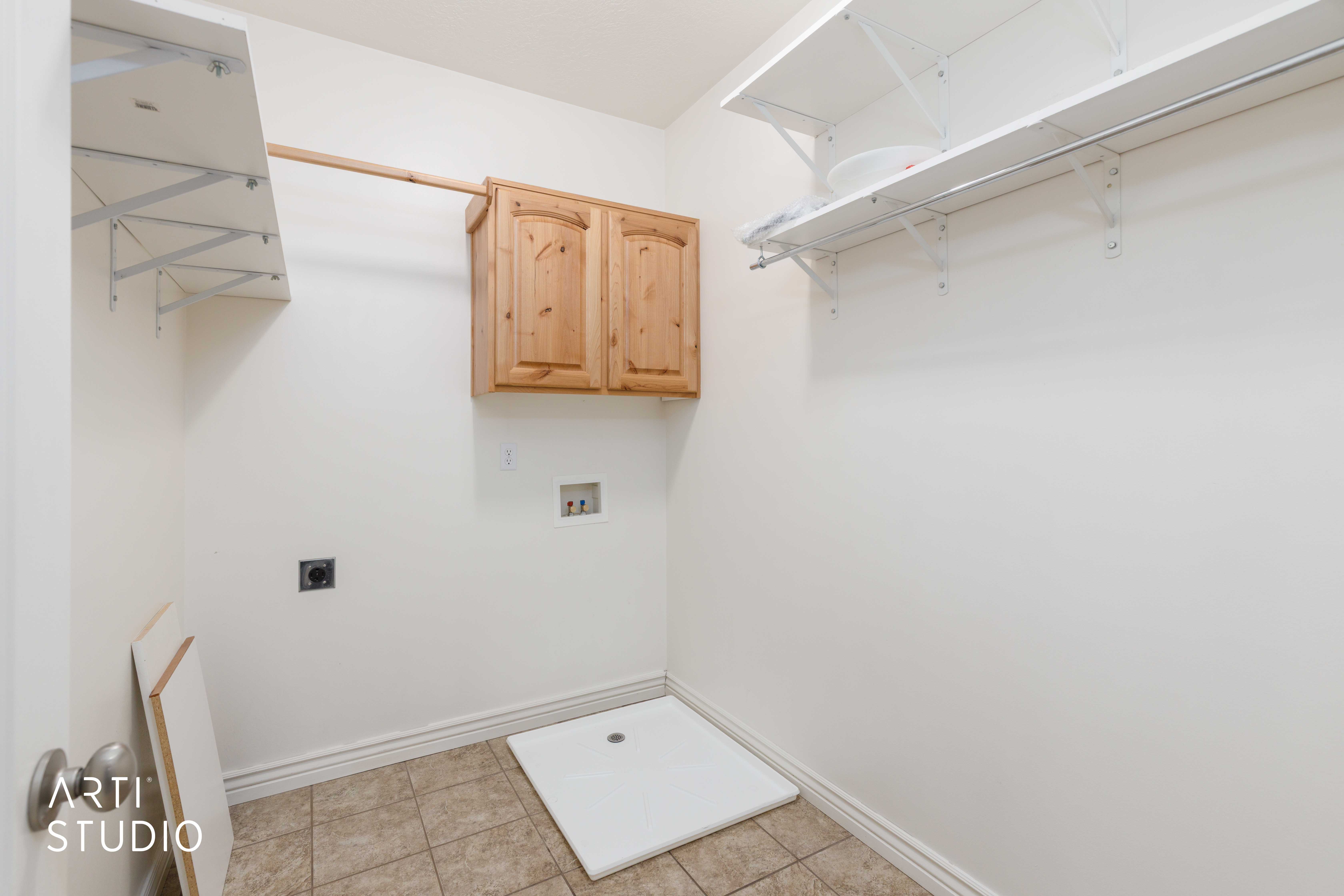 Utility room featuring built-in shelving, wall-mounted cabinetry, tile flooring, and appliance hookups