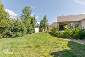 Expansive backyard featuring a manicured lawn, established landscaping, and a covered patio