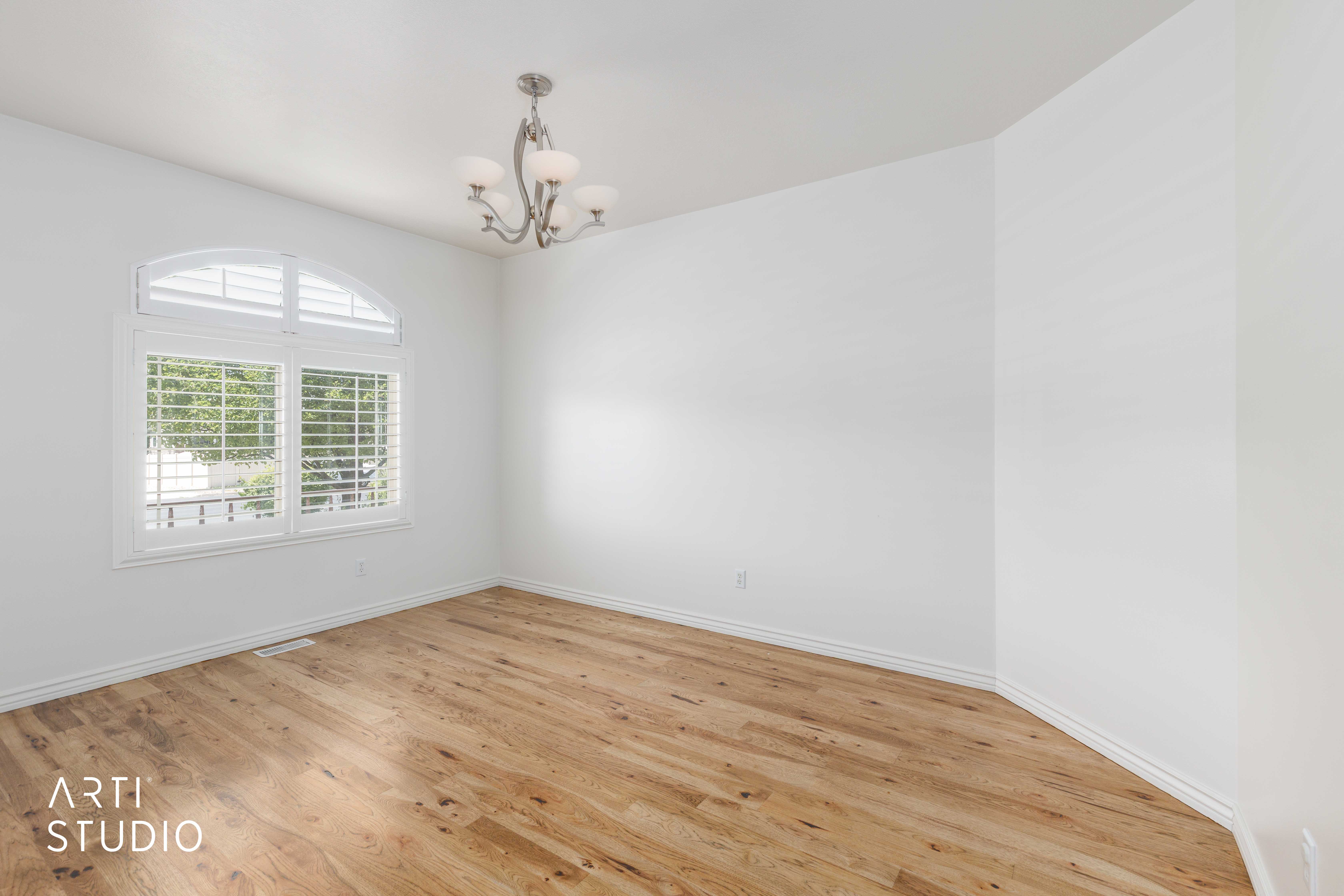 Bright interior space featuring wood-finish flooring, white walls, and a five-light chandelier