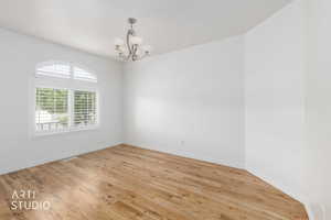 Bright interior space featuring wood-finish flooring, white walls, and a five-light chandelier