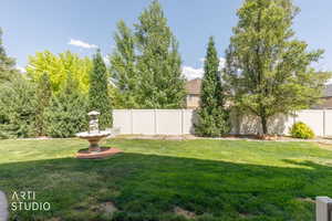 Expansive lawn area featuring a decorative garden fountain on a paver base, surrounded by mature trees and evergreen shrubs