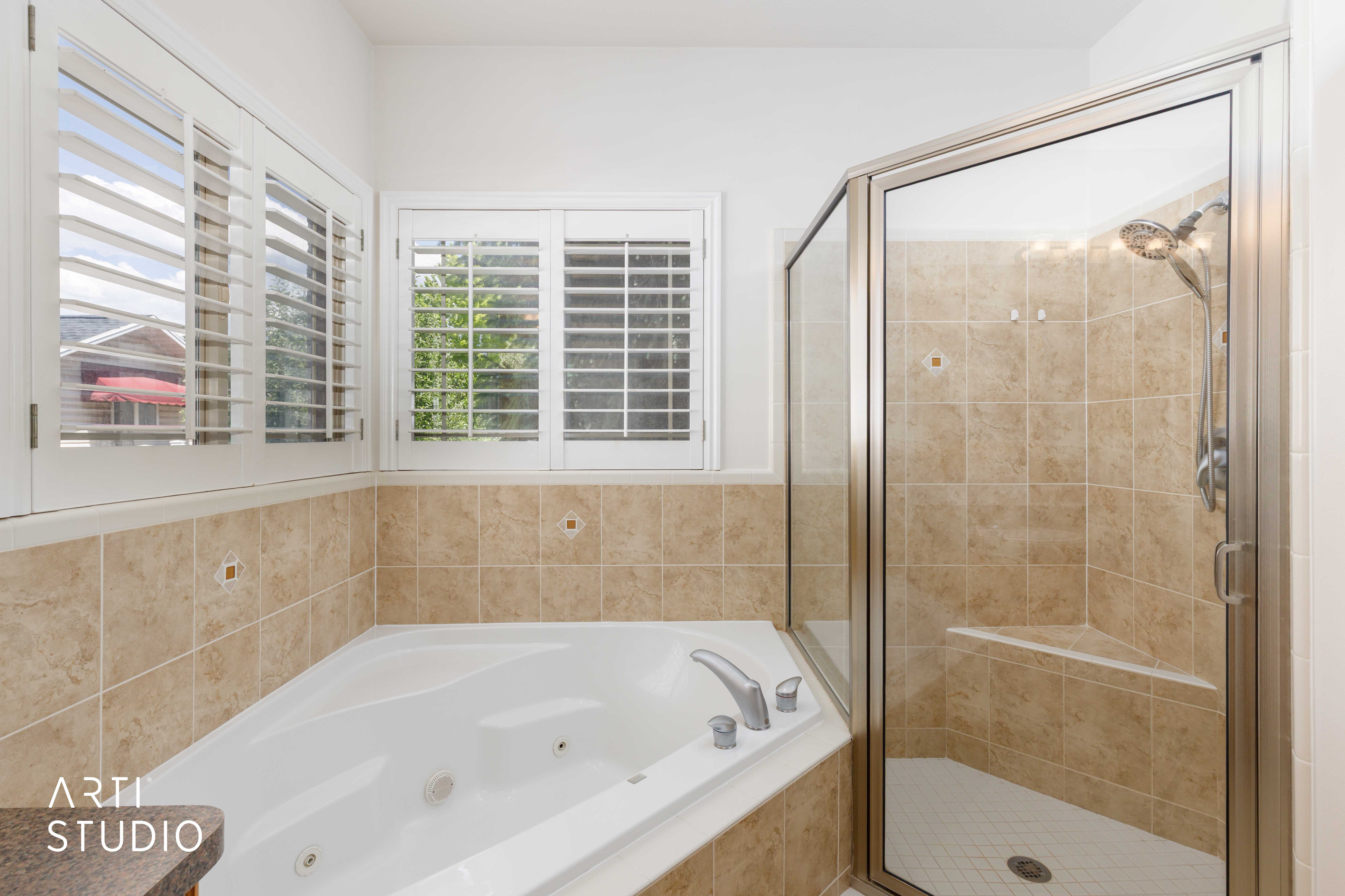 Corner soaking tub and a separate glass-enclosed shower with a built-in bench