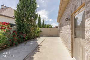 Side yard featuring a concrete pathway, mature evergreen trees, and a privacy fence