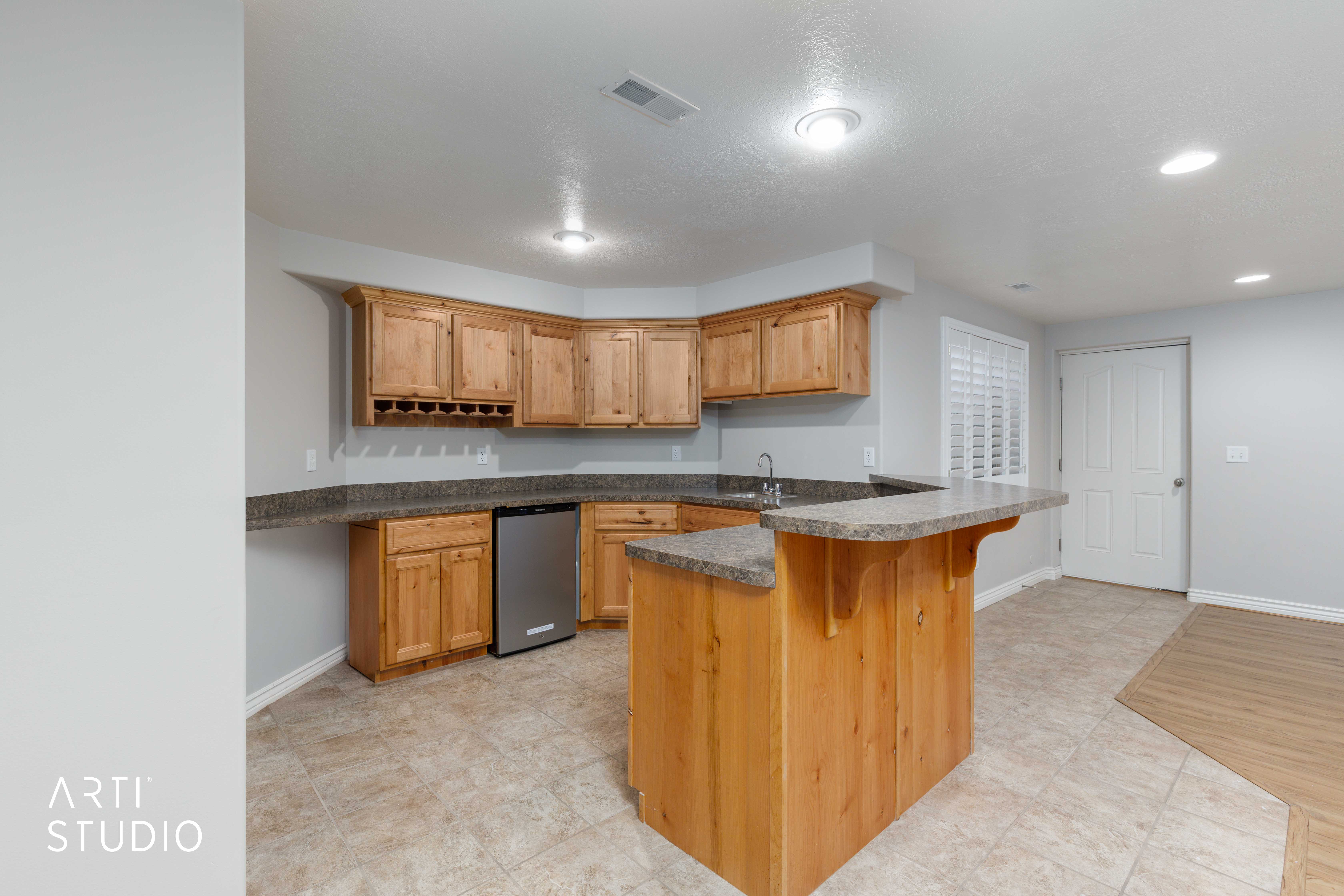Corner kitchen or wet bar featuring wood cabinetry, integrated wine rack, and a stainless steel under-counter refrigerator