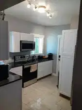 Kitchen featuring white shaker-style cabinetry, dark countertops, stainless steel appliances, and track lighting