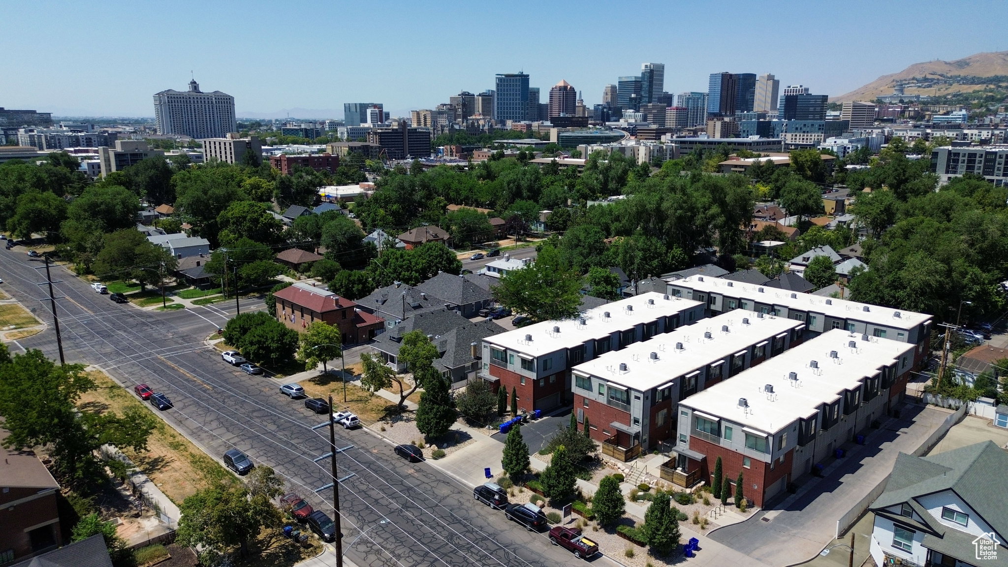 Contemporary townhome development featuring a brick and panel exterior, private patios, and a city skyline backdrop