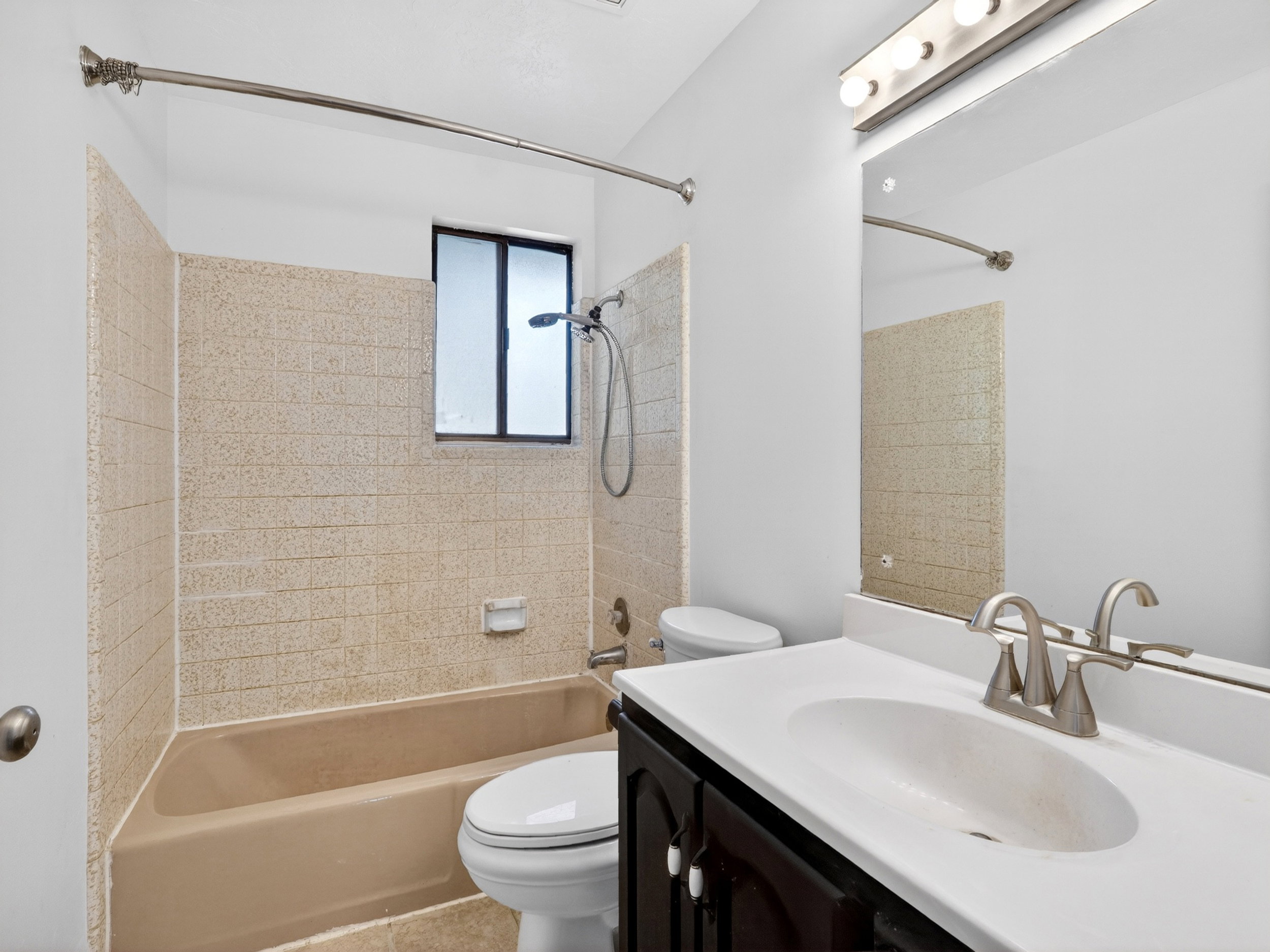 Bathroom featuring a dark wood-finish vanity with a white integrated sink, brushed nickel faucet, and a large wall-mounted mirror