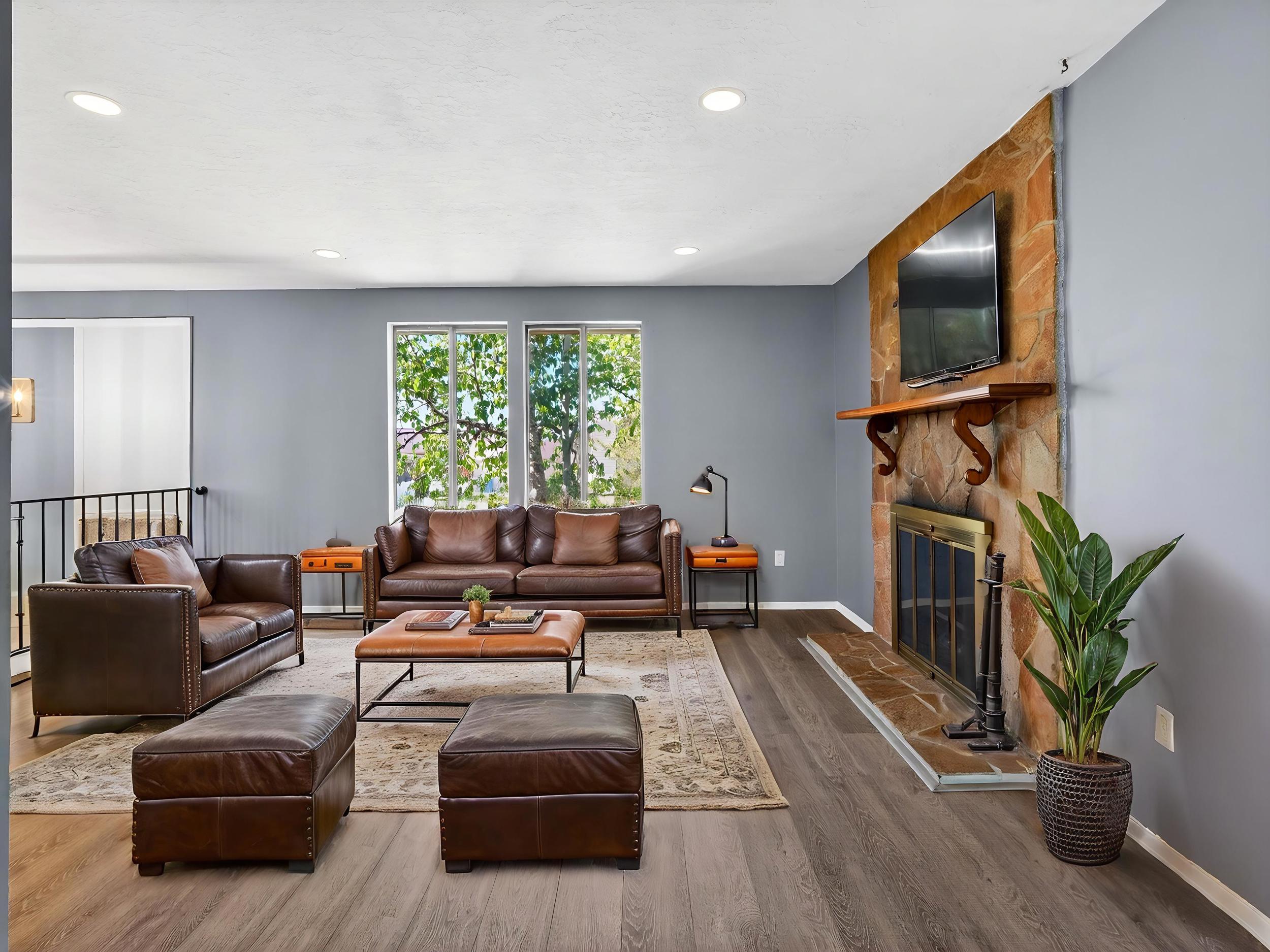 Living area featuring wood-finish flooring, a stone-clad fireplace with a decorative mantel, and recessed ceiling lighting