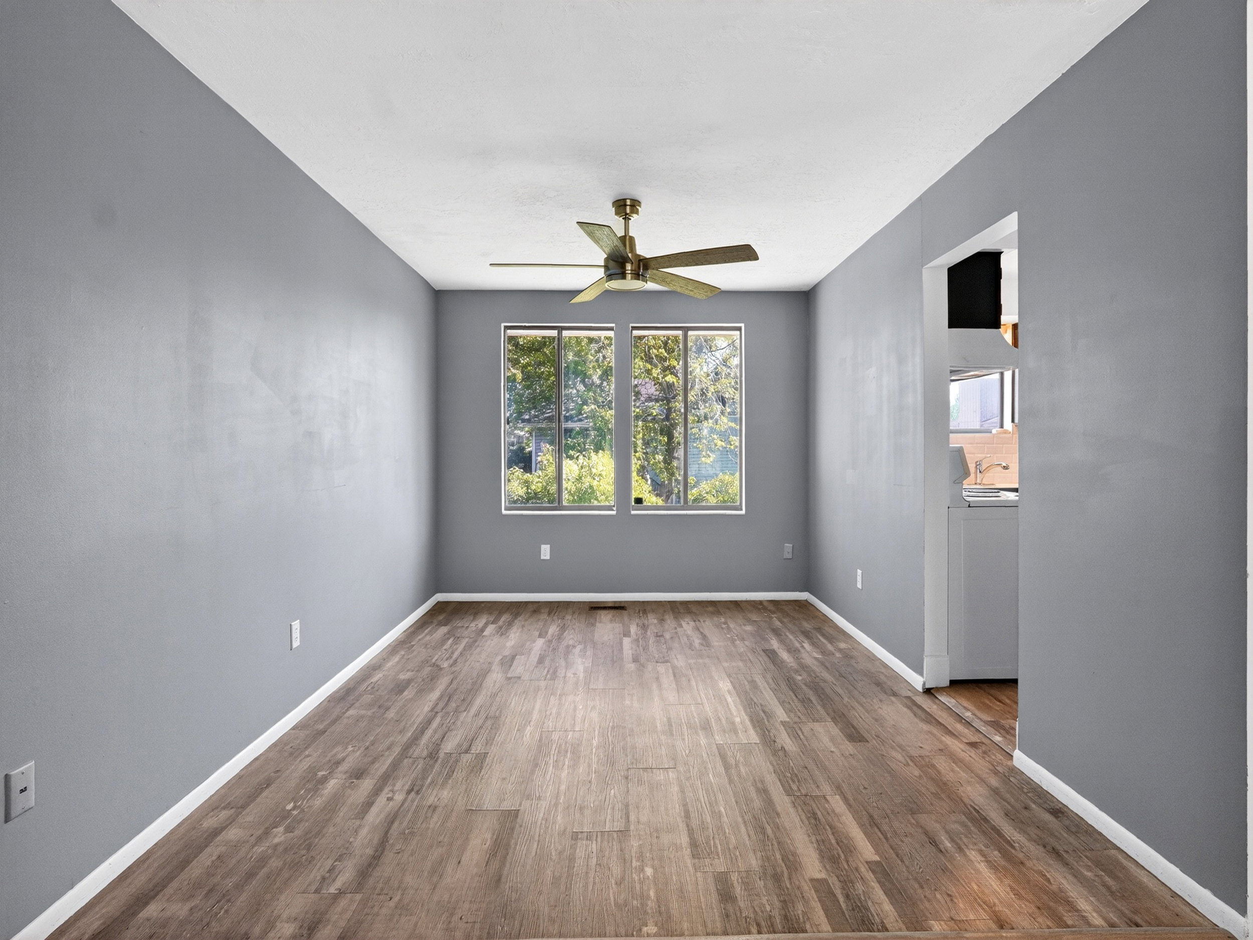 Spacious room featuring wood-finish flooring, light gray walls, and white baseboards