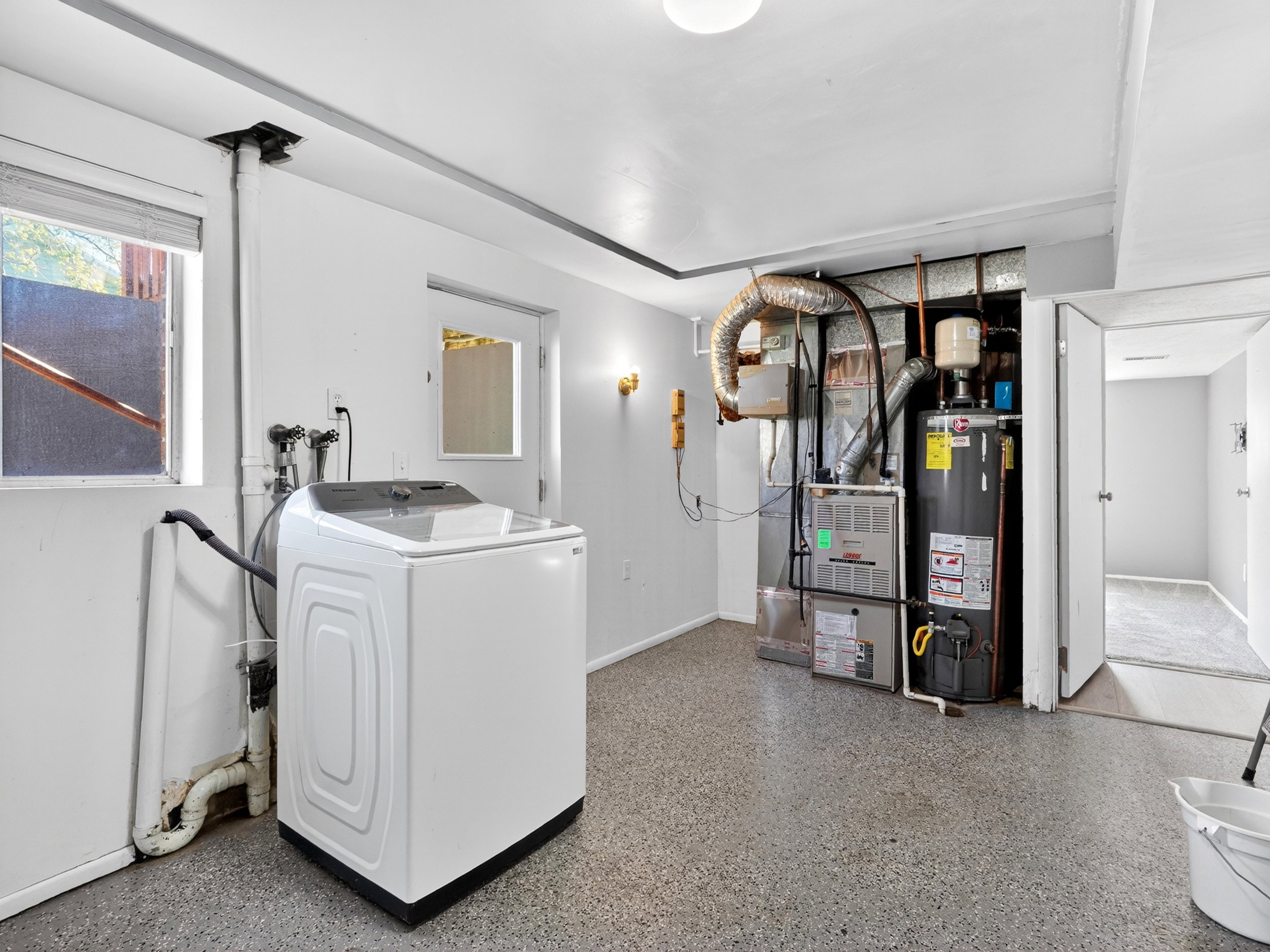 Dedicated laundry area featuring a utility sink connection, window for natural light, and durable speckled flooring