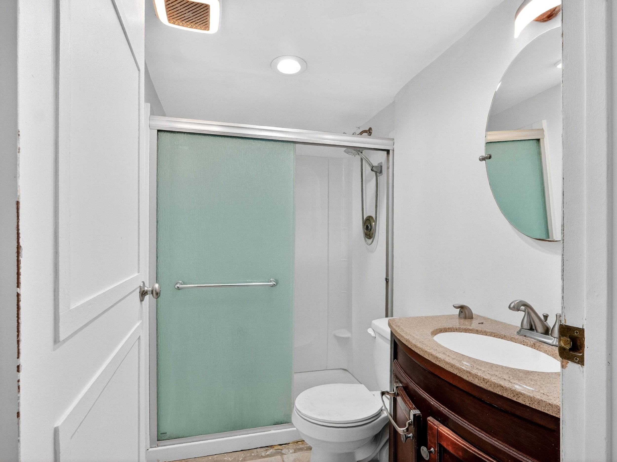 Bathroom featuring a shower with frosted sliding glass doors, a vanity with a dark wood-finish cabinet, and a countertop with an integrated sink