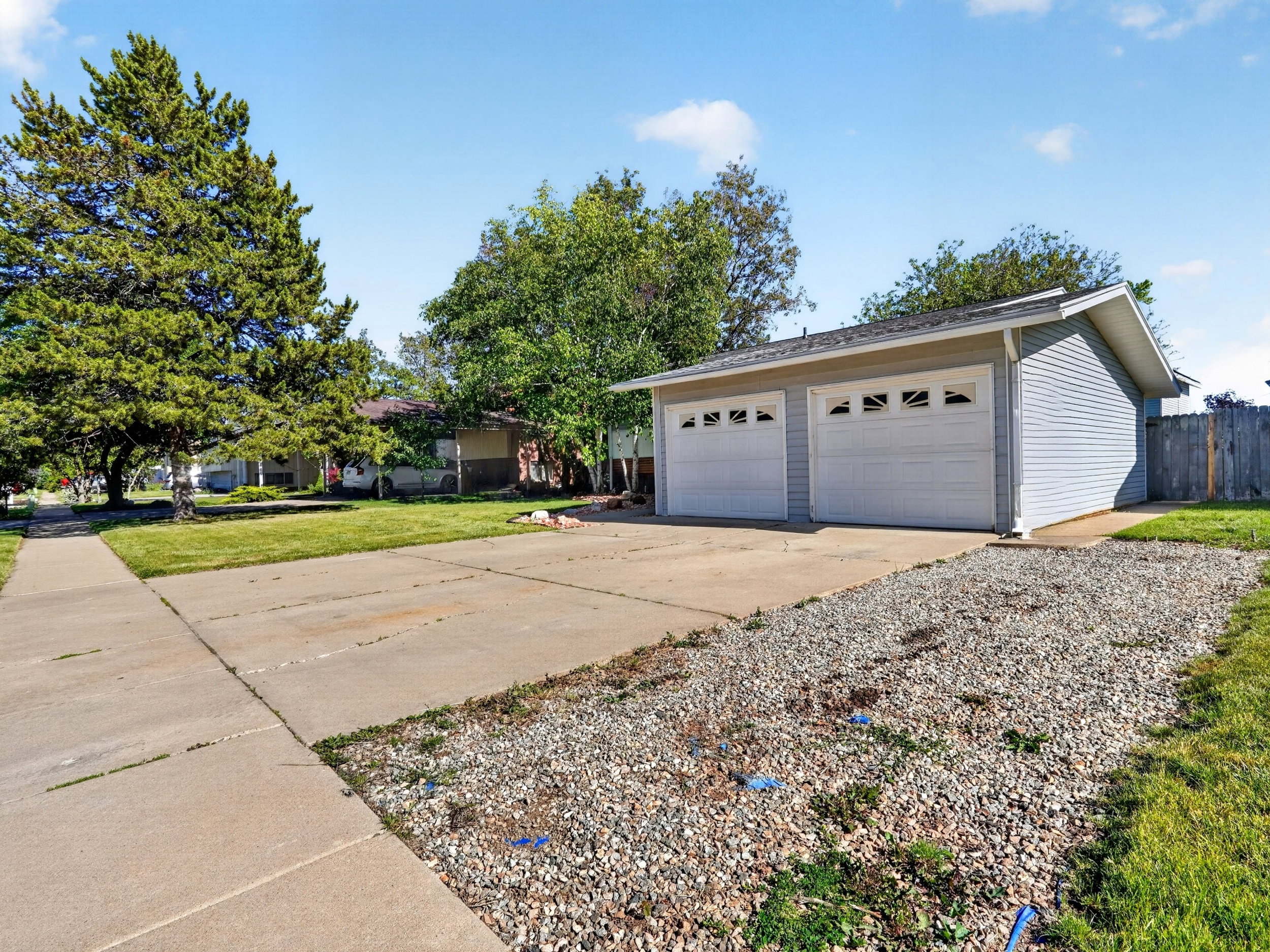 Two-car detached garage with light blue siding and white paneled garage doors