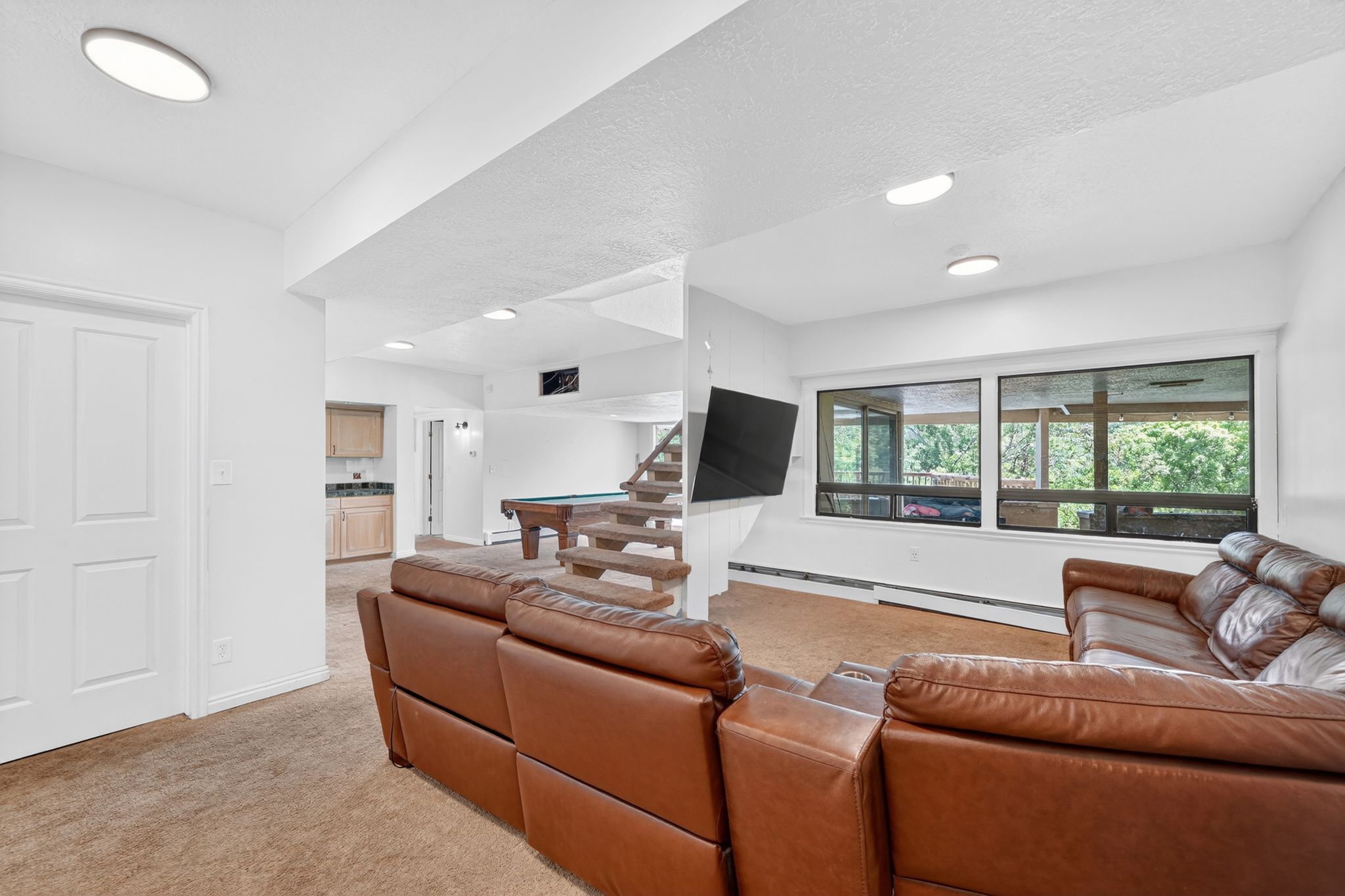 Spacious lower-level living area with recessed lighting and neutral carpeting