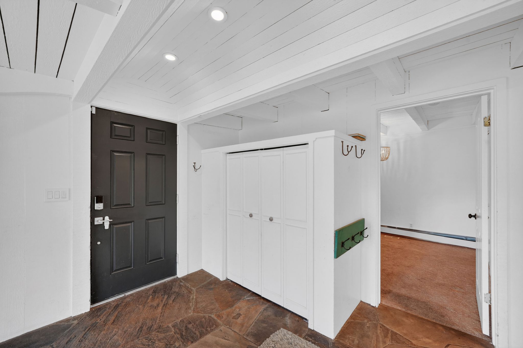Entryway featuring natural stone flooring, a dark panel door, and recessed lighting