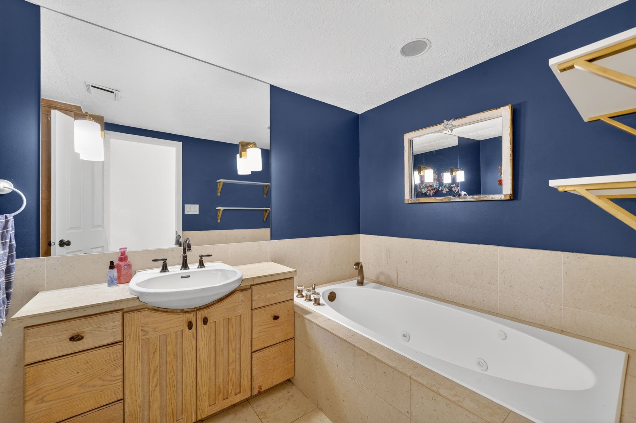 Bathroom featuring a built-in jetted tub, single vanity with a vessel sink, and a full-width wall mirror