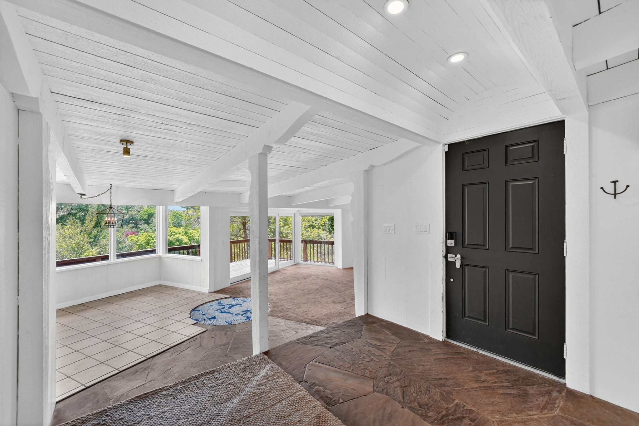Entryway featuring a paneled black door with smart lock, recessed lighting, and flagstone flooring