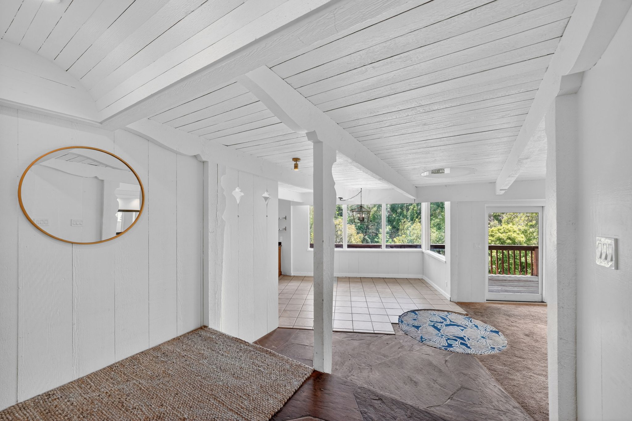 Inviting interior featuring white wood-paneled walls and ceiling, exposed ceiling beams, and a combination of tile and wood-finish flooring