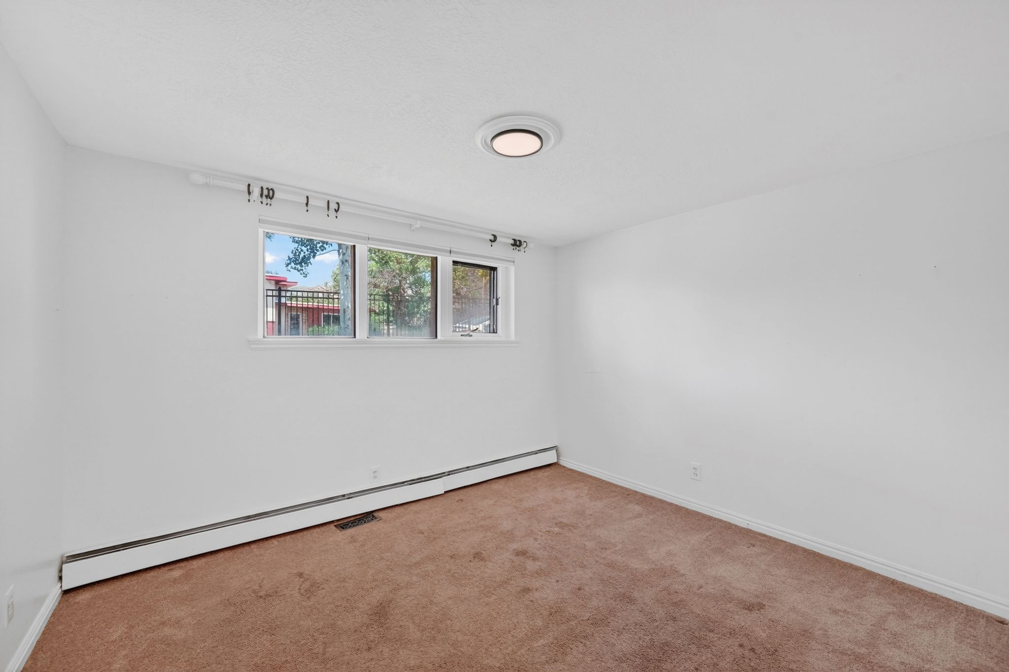 Room featuring a window with exterior views, white walls, and brown carpet flooring