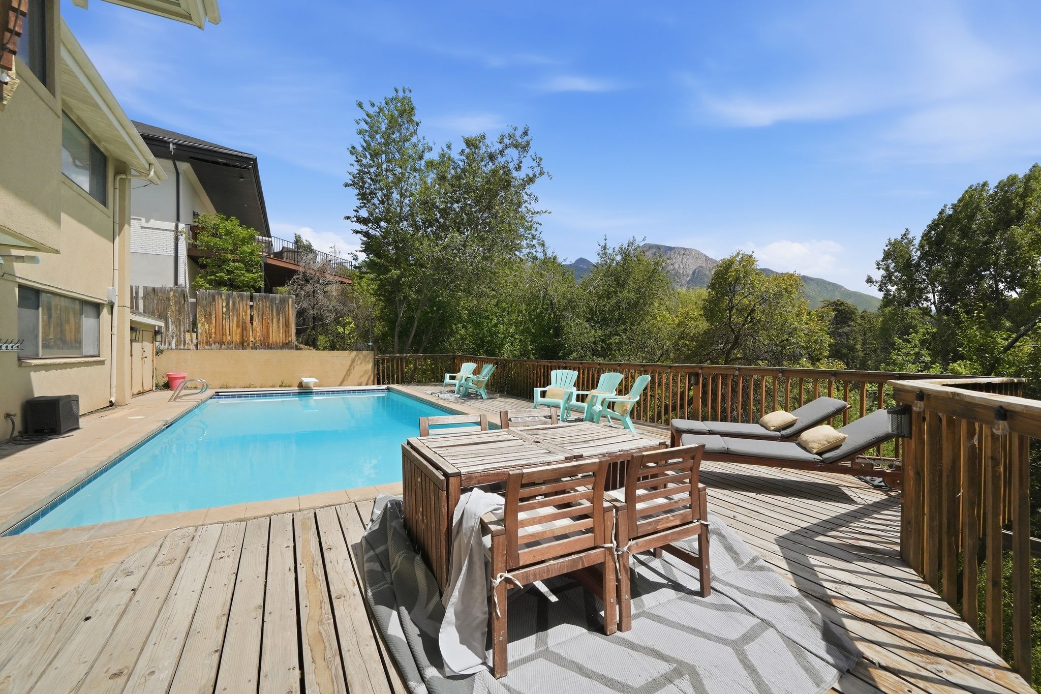 Expansive outdoor deck featuring an inground swimming pool, surrounding wooden deck, and mountain scenery