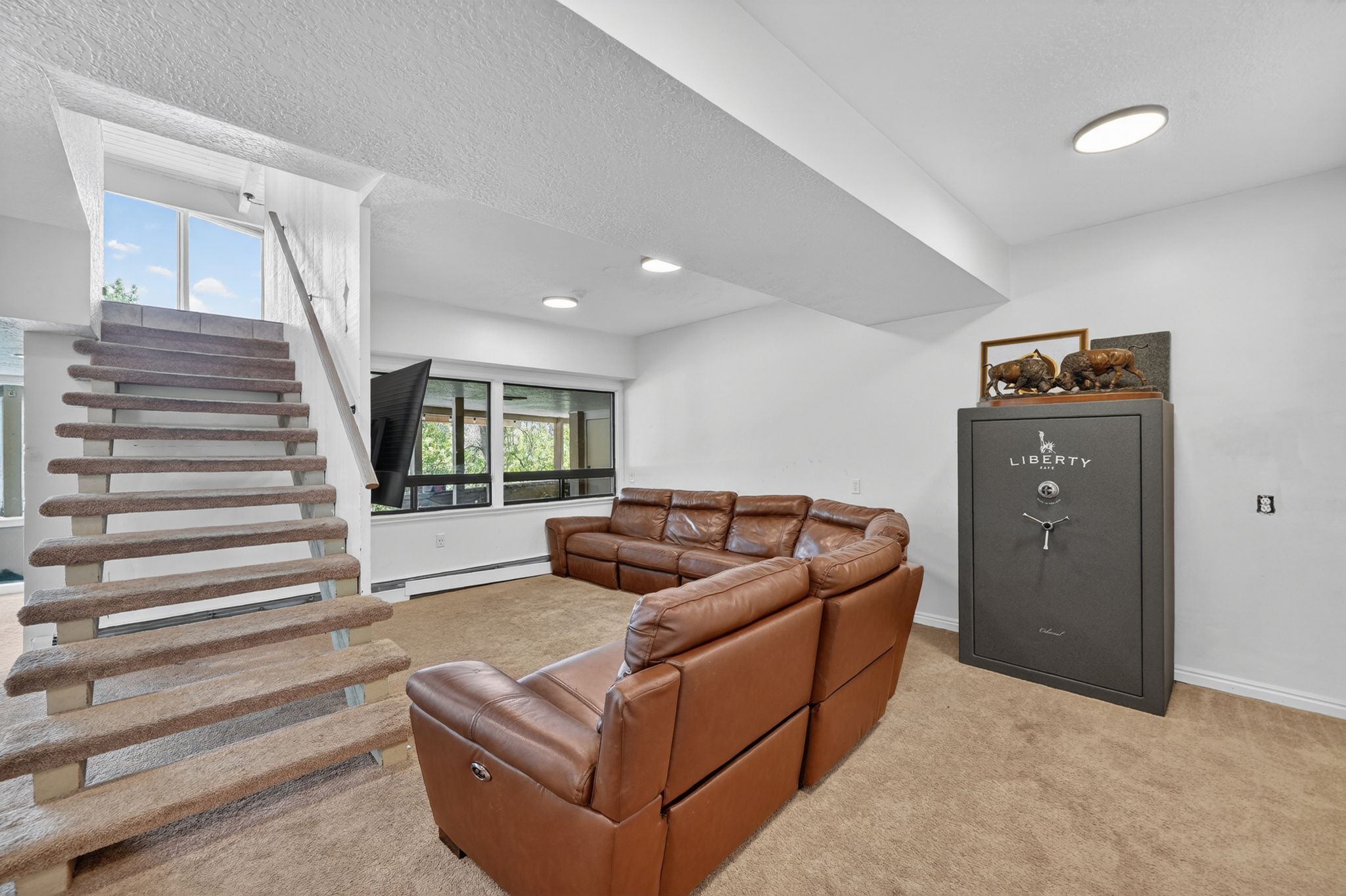 Lower-level living area with carpeted flooring and recessed ceiling lighting