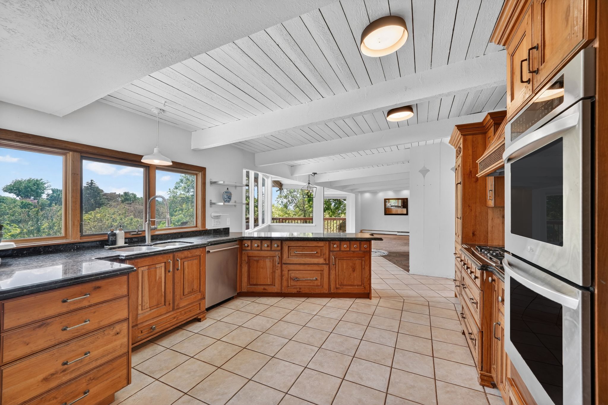 Open-concept kitchen featuring extensive wood cabinetry, tile flooring, and integrated stainless steel double ovens