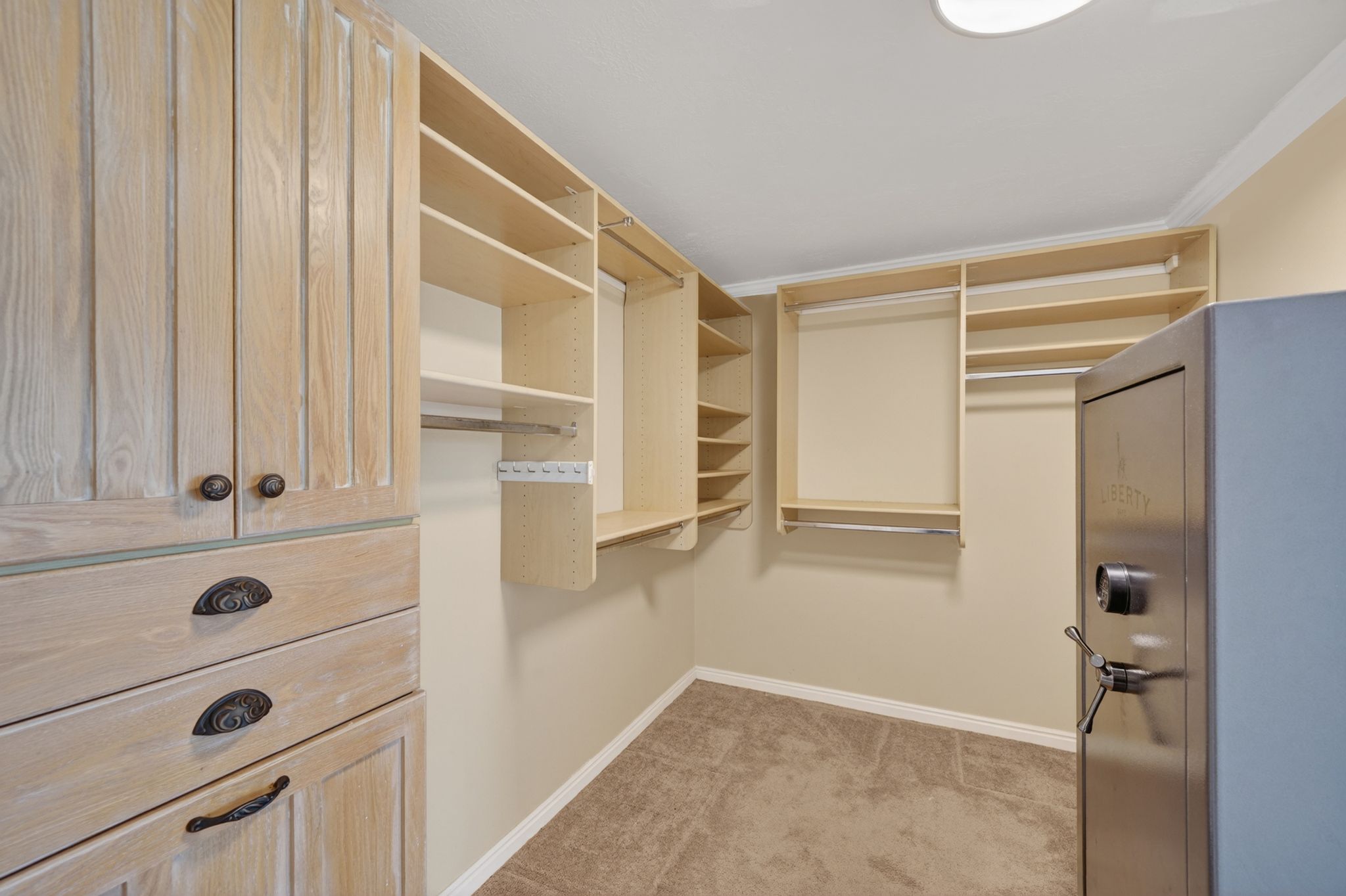 Custom closet organization system featuring light wood-finish cabinetry, integrated shelving, and hanging rods