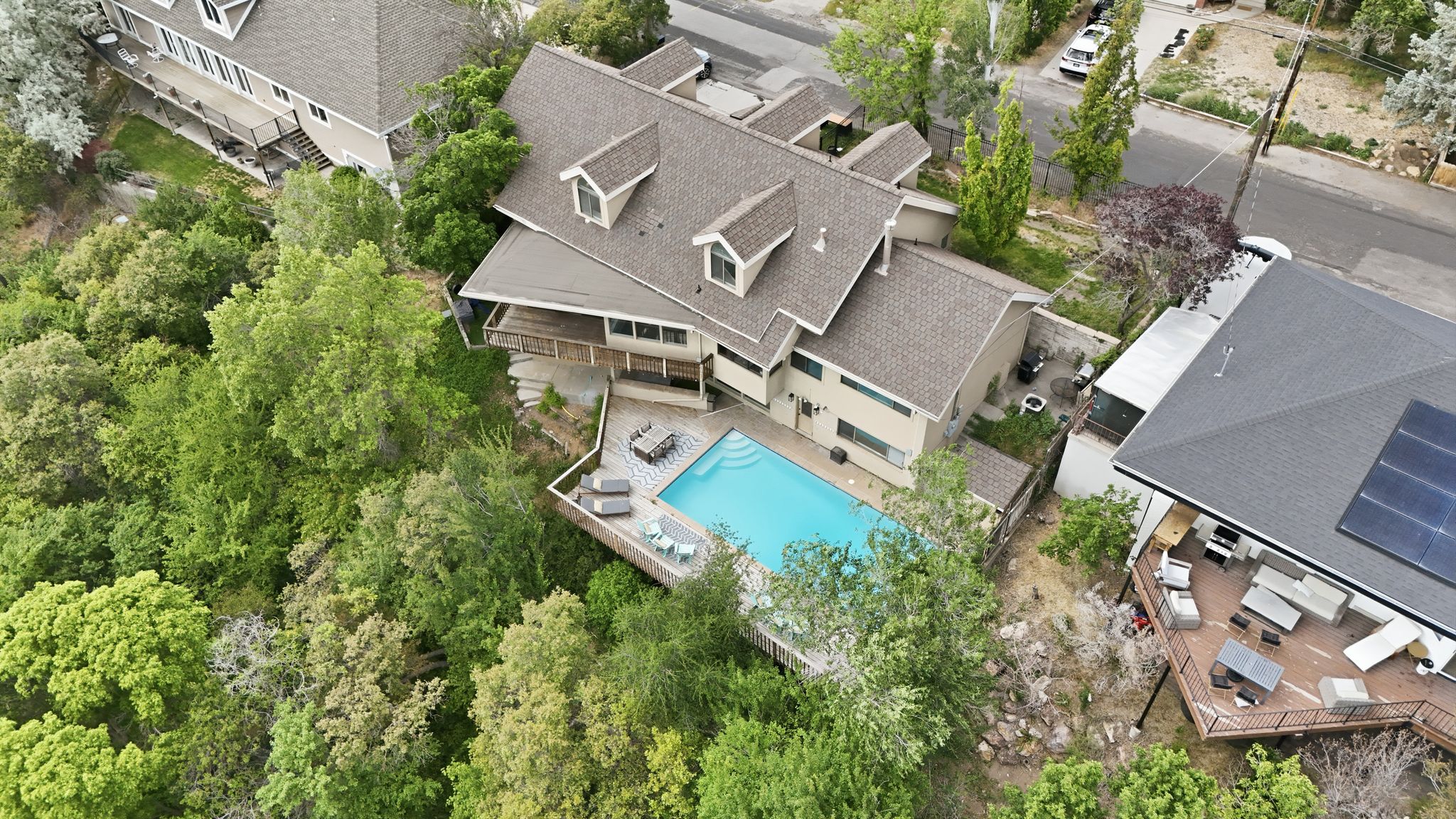 Multi-level residence featuring a swimming pool, surrounding patio, and an elevated wood deck