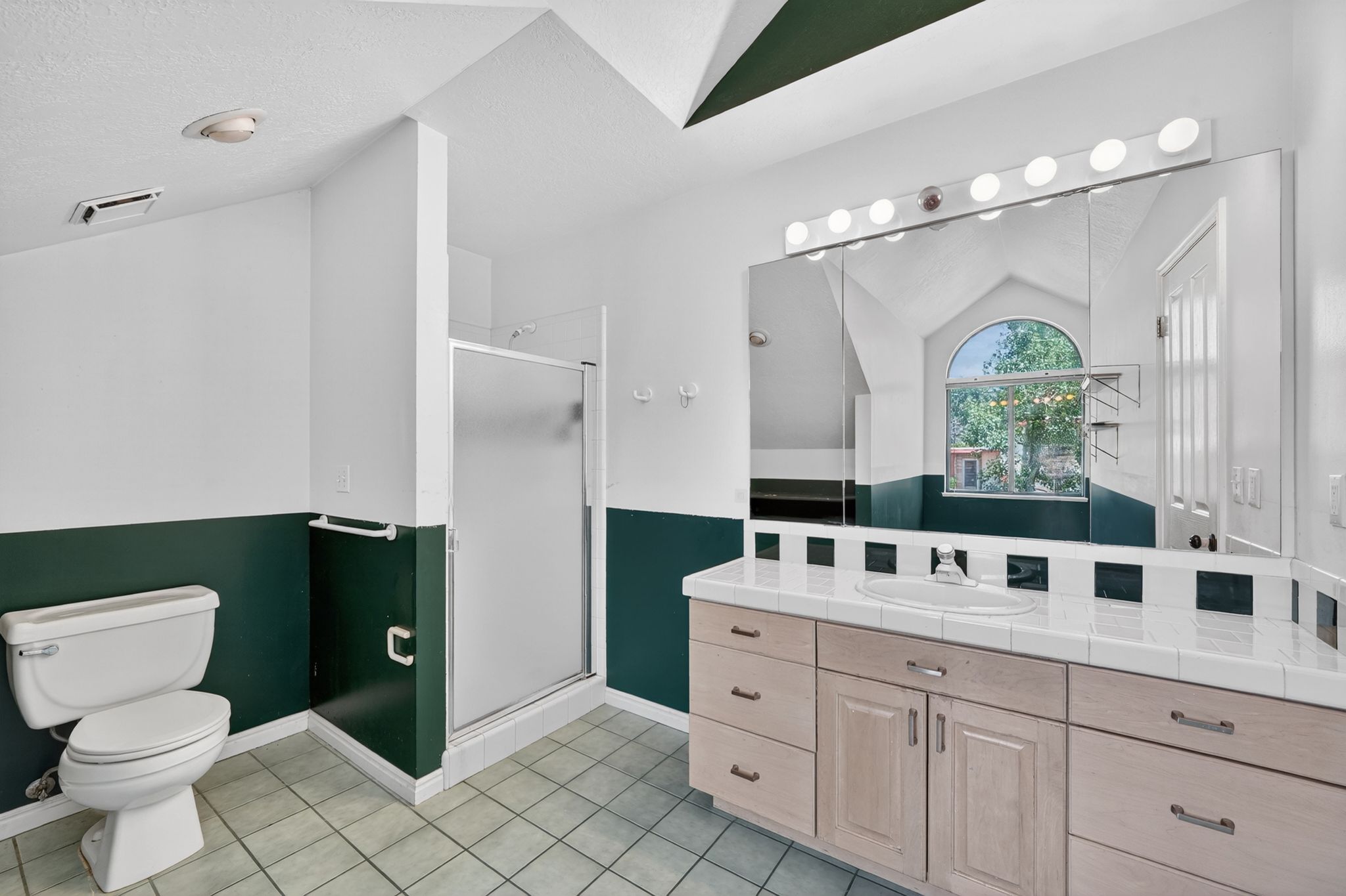 Bathroom featuring a spacious vanity with an integrated sink and an expansive mirror with Hollywood-style lighting