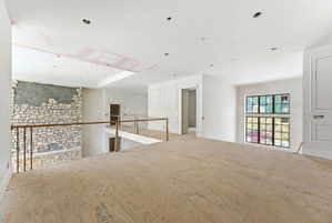 Spacious upper-level area featuring a stone accent wall, recessed lighting, and a prominent window array with black framing