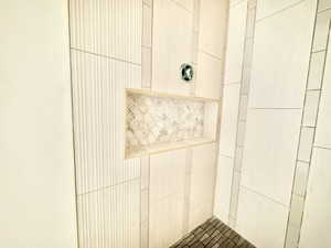 Shower enclosure featuring a tiled niche with mosaic accent, textured vertical wall tiling, flat panel wall tiling, and a dark tile mosaic floor