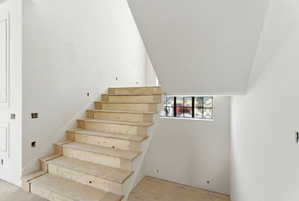 Unfinished wooden staircase with a glass block window and white walls