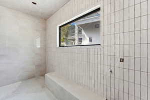 Tiled shower enclosure featuring vertical stacked rectangular tiles and a horizontal black-framed window