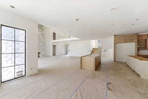 Open-concept living area featuring a stone-clad fireplace and large multi-pane windows