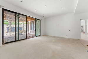 Expansive interior space featuring a large sliding glass door, recessed ceiling lighting, and a neutral color palette