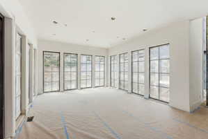Spacious room featuring multiple large grid-pattern windows, recessed lighting, and crisp white walls