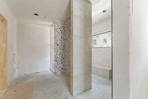 Walk-in shower with decorative tiled wall, full-height glass panel, and built-in bench