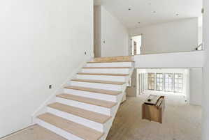 Grand staircase featuring light wood-finish treads and white risers