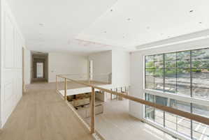 Spacious upper-level landing with light wood-finish flooring, recessed lighting, and a large multi-pane picture window