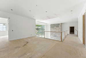 Open concept upper level featuring a stone-clad architectural feature, glass panel railing, recessed lighting, and large windows