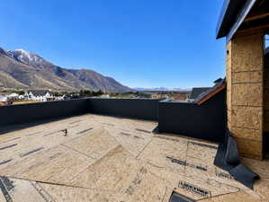 Expansive rooftop deck under construction, featuring partial framing and a mountain backdrop