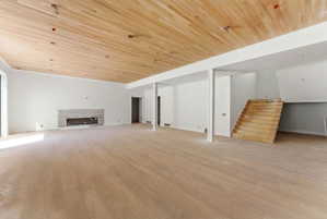 Spacious room featuring wood-finish flooring, a complementary wood-plank ceiling, and a built-in fireplace