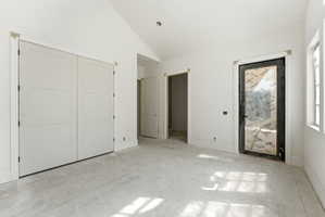 Spacious room featuring vaulted ceilings, a large paneled bi-fold door, a black-framed door with a glass insert, and window openings