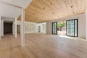 Expansive interior space featuring light wood-finish flooring, a coordinating wood-paneled ceiling with recessed lighting, and a prominent decorative wall paneling