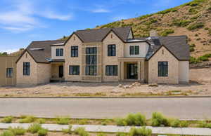 Stone and stucco exterior featuring a prominent two-story window wall
