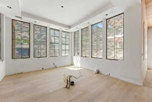 Room featuring extensive grid-patterned windows, light wood-finish flooring, and recessed ceiling lighting