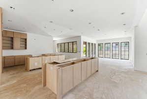 Spacious open-concept interior featuring light-toned cabinetry, recessed lighting, and expansive multi-pane windows